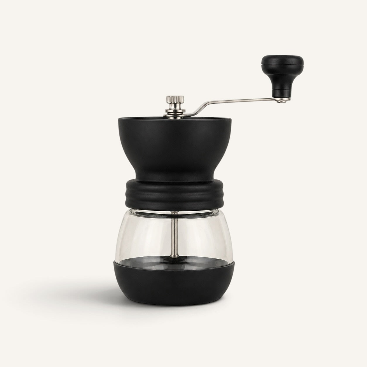 BrewCups siyah manuel kahve öğütücü, şeffaf cam haznesi ve ergonomik çevirme kolu ile modern mutfak tasarımı.